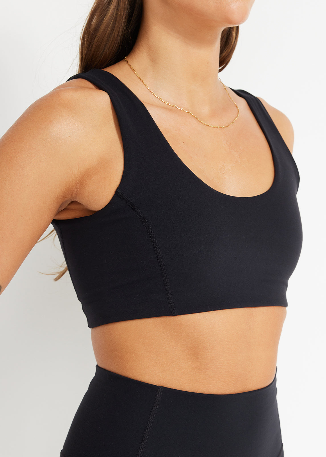 Close-up of black scoop crop showing soft stretch fabric and clean seam detail