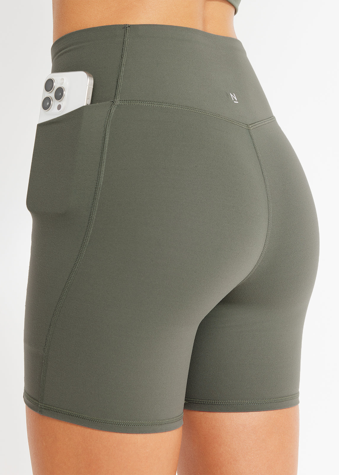 Close-up of model wearing olive green bike shorts with phone in her side pocket