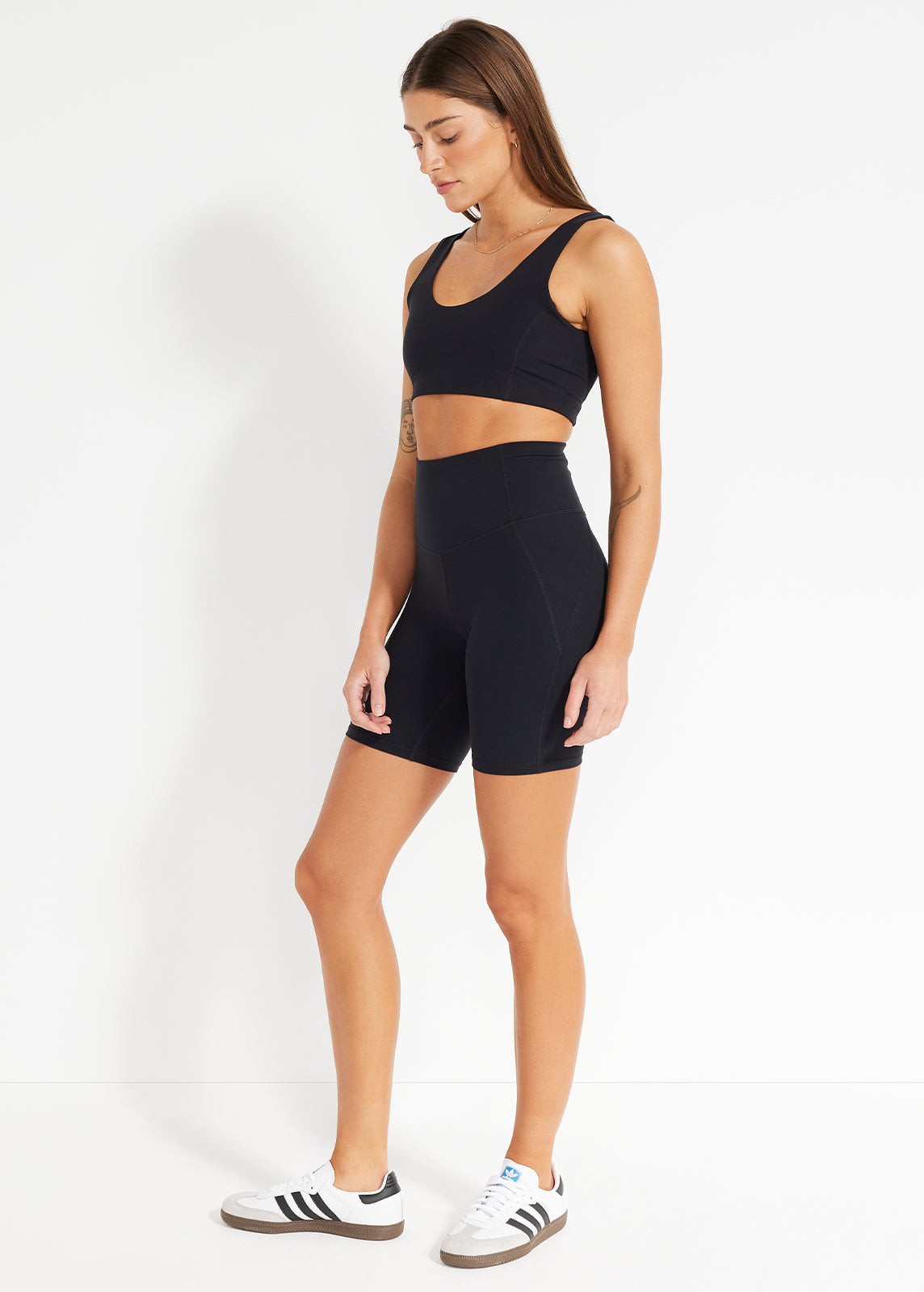 Side view of black scoop bra and high-rise bike shorts styled with white sneakers