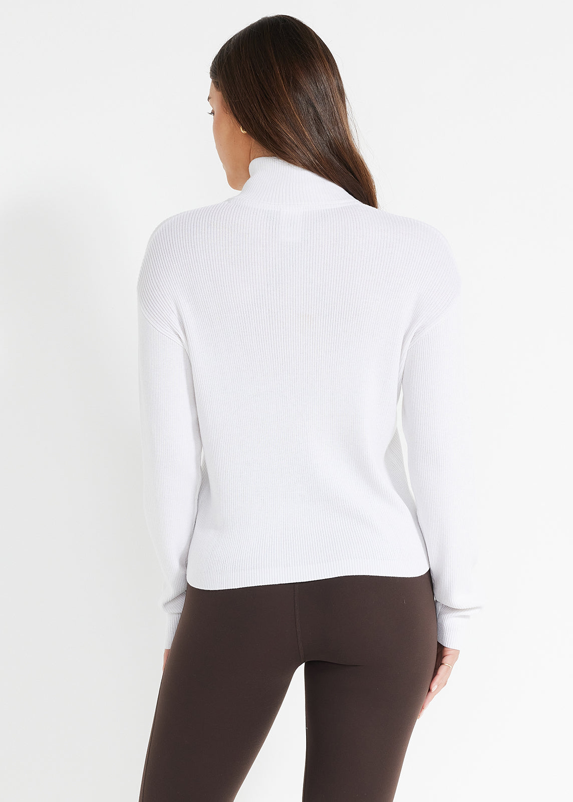 Back view of white ribbed jumper paired with brown leggings