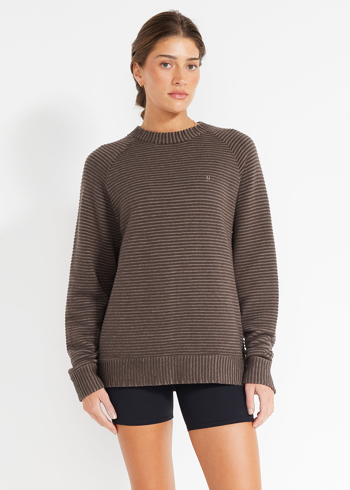 Model wearing brown striped knit jumper paired with black bike shorts